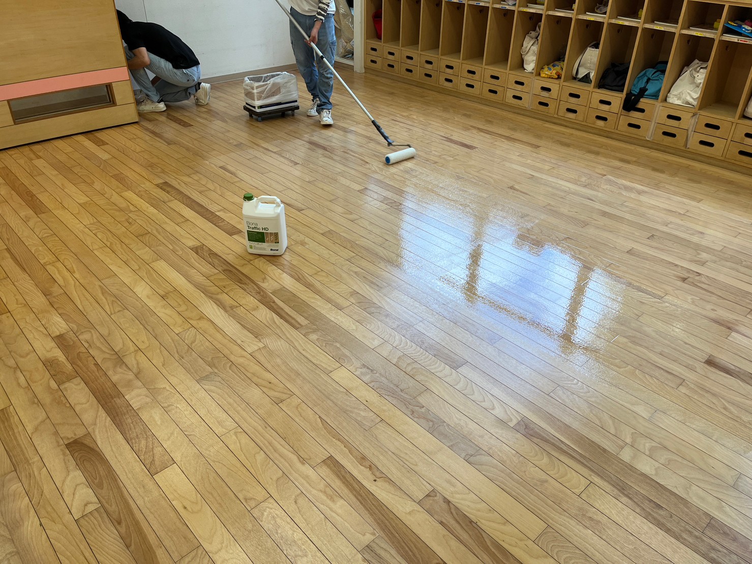 木床へローラーで仕上げ塗料を施工している様子